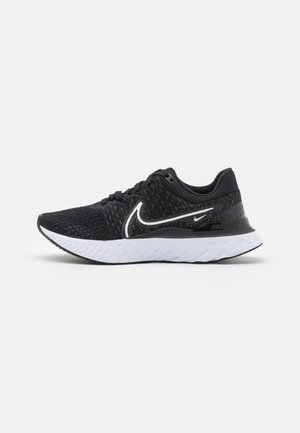 Baskets de sport noires avec un dessus en tricot texturé, semelle blanche et accents noirs. Présente un logo Nike en blanc bien visible sur le côté.