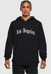 Felpa nera con tasca frontale, presenta "Los Angeles" in caratteri bianchi stilizzati sulla parte anteriore, realizzata in materiale morbido e resistente.