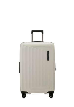 Hard-shell suitcase in off-white, featuring a ribbed design, black handle, and four spinner wheels for easy mobility.
