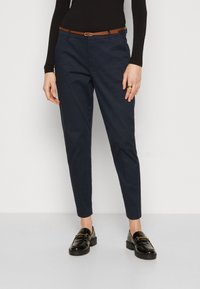 Navy blue dress pants with a tailored fit and belt loops, featuring a brown leather belt. Paired with black loafers. Smooth cotton fabric.