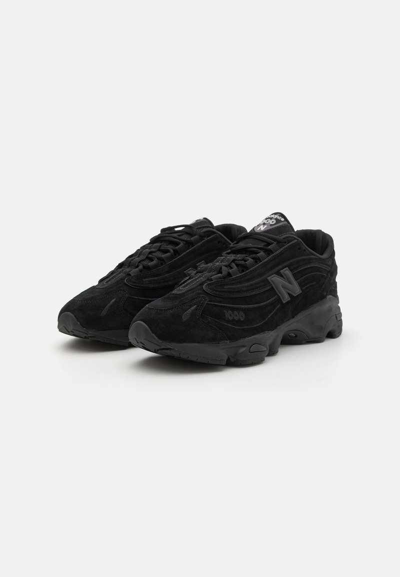 Zapatillas de ante negro con un diseño texturizado, que presentan una puntera redondeada, un cuello acolchado y un prominente logo "N" negro en el lateral.
