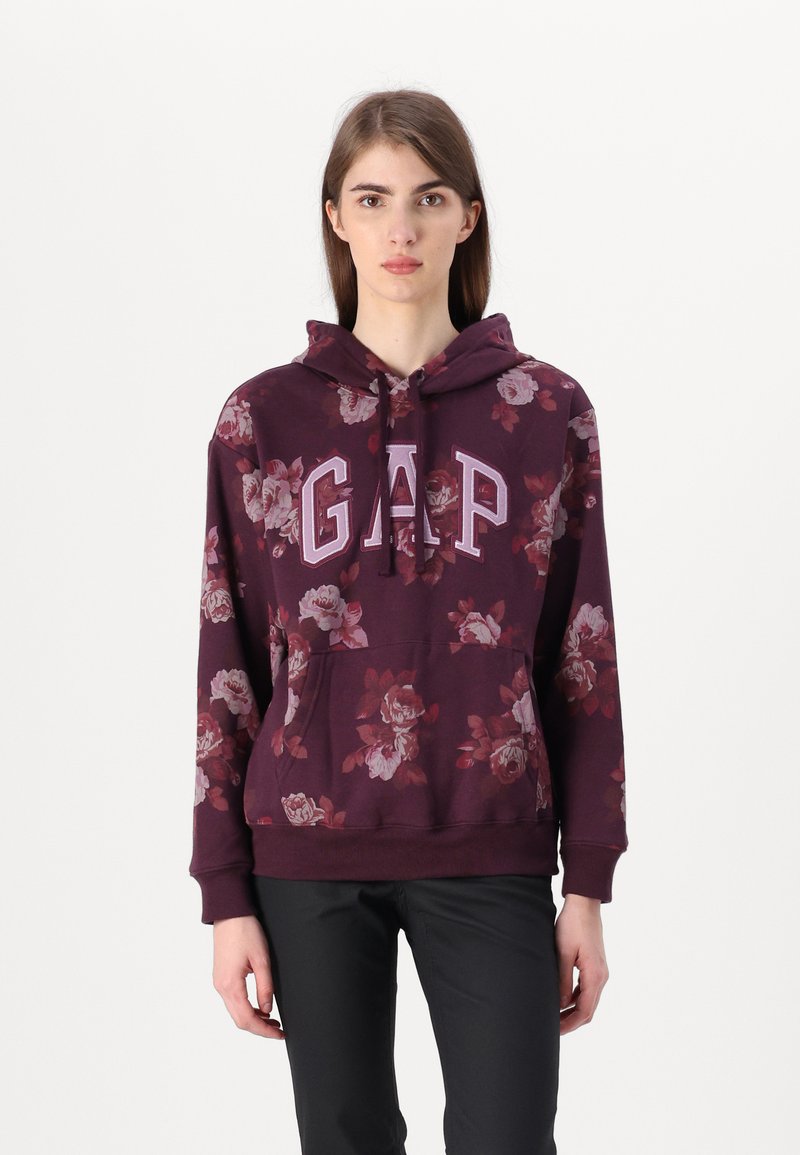 Hanorac floral mov cu logo "GAP" în alb. Include un buzunar tip cangur și glugă cu șnur, fabricat din material moale de bumbac.