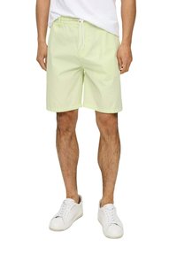 Lichtgroene katoenen shorts met een elastische tailleband en trekkoord. Inclusief zijzakken en een rechte zoom, gedragen met witte sneakers.