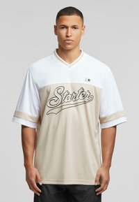 Beige and white short-sleeve jersey with a v-neck, featuring “Starter” in black script across the chest and contrasting stripes on sleeves.