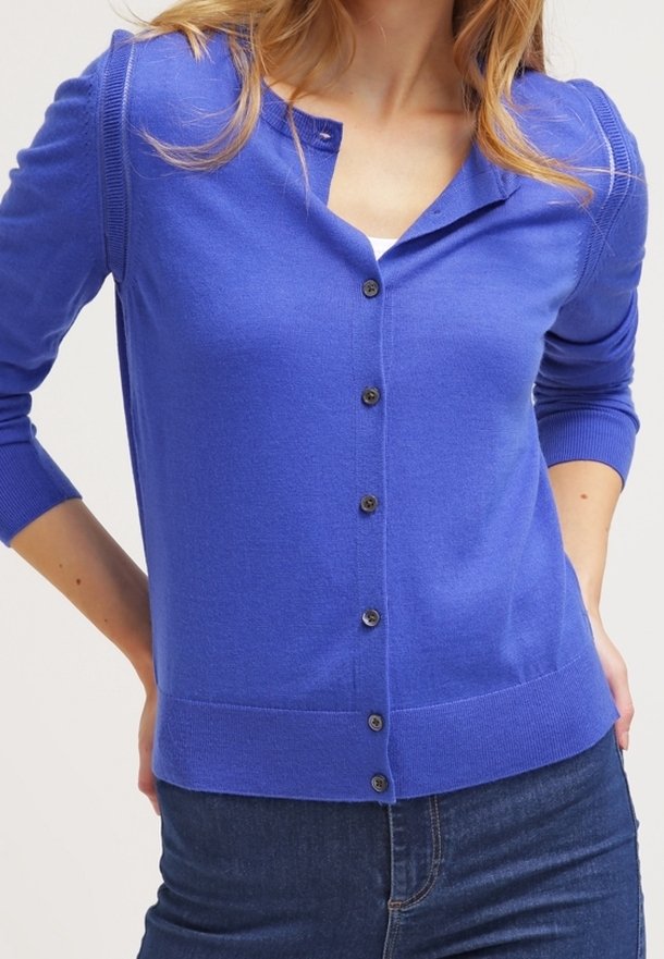 Královsky modrý svetr na knoflíky, rukávy střední délky, výstřih do "V", se šesti tmavými knoflíky na přední straně a žebrovaným lemem. Měkká textura.