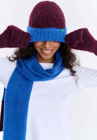 Dziana czapka typu beanie w kolorze bordowym i niebieskim, do kompletu rękawiczki i szalik. Miękka tekstura, zaokrąglony kształt, czapka z zielonym akcentem.