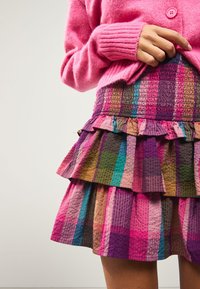 Gonna a più strati multicolore con orlo ondulato, realizzata in tessuto strutturato. Presenta motivi a blocchi nei colori rosa, viola, verde e marrone.