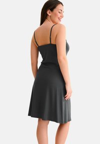 Robe gris foncé avec de fines bretelles réglables, corsage ajusté et ourlet évasé. Tissu lisse et léger avec une texture douce.