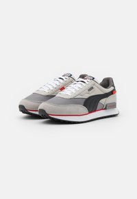 Gray and black athletic shoes with suede and textile upper, white laces, red accents, and a white soles featuring a textured grip pattern.