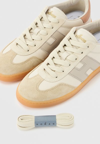 Μπεζ αθλητικά παπούτσια με υλικά σουέτ και δέρμα, διαθέτουν στρογγυλή μύτη, δέσιμο με κορδόνια και ελαστική σόλα. Περιλαμβάνονται επιπλέον κορδόνια.