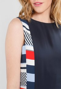 Vestido de marino que presenta una tela sólida en un lado y un patrón de rayas multicolores en el otro, con una textura suave y un diseño sin mangas.