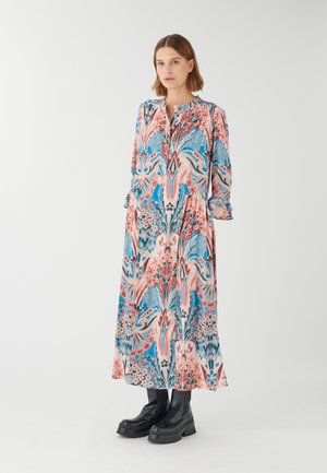 Langes pinkes und blauflorales Kleid mit rundem Halsausschnitt, Knopfleiste und Rüschenärmeln, kombiniert mit klobigen schwarzen Plateaustiefeln.