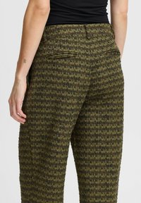 Pantalons texturés vert et noir à motif, avec une coupe décontractée, dotés de poches arrière et d'une taille haute.