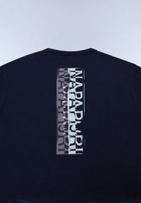 Námořnická mikina s vertikálním grafickým potiskem na zadní straně, s vrstvenými textovými prvky v bílé a šedé barvě, která ukazuje moderní design.