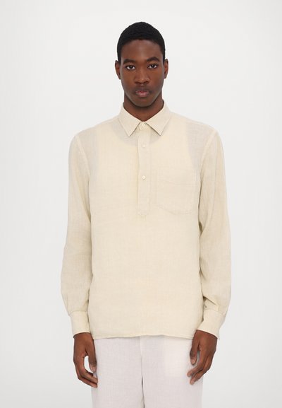 Chemise en lin beige clair à manches longues, avec un col boutonné et une poche poitrine. Texture légère avec une coupe décontractée.