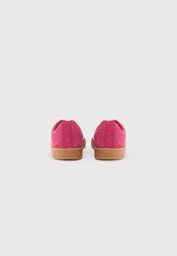 Scarpe di camoscio rosa con profilo basso e suole in gomma beige. Presentano un retro arrotondato e dettagli di cucitura minimali.