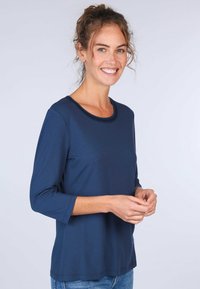 Marineblaues Langarmshirt aus weichem Material mit Rundhalsausschnitt und ohne sichtbare Muster oder Hardware, kombiniert mit lässiger Denim.