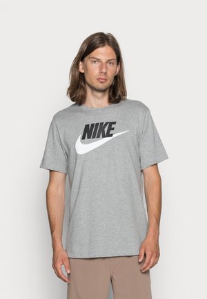 T-shirt in cotone grigio con un grande logo Nike nero e uno swoosh bianco. Maniche corte, vestibilità comoda e scollatura rotonda.