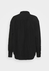 Schwarzes langärmeliges Hemd aus Baumwolle mit legerer Passform, klassischem Kragen und Knopfmanschetten. Die Rückseite ist mit einem plisseeartigen Design versehen.