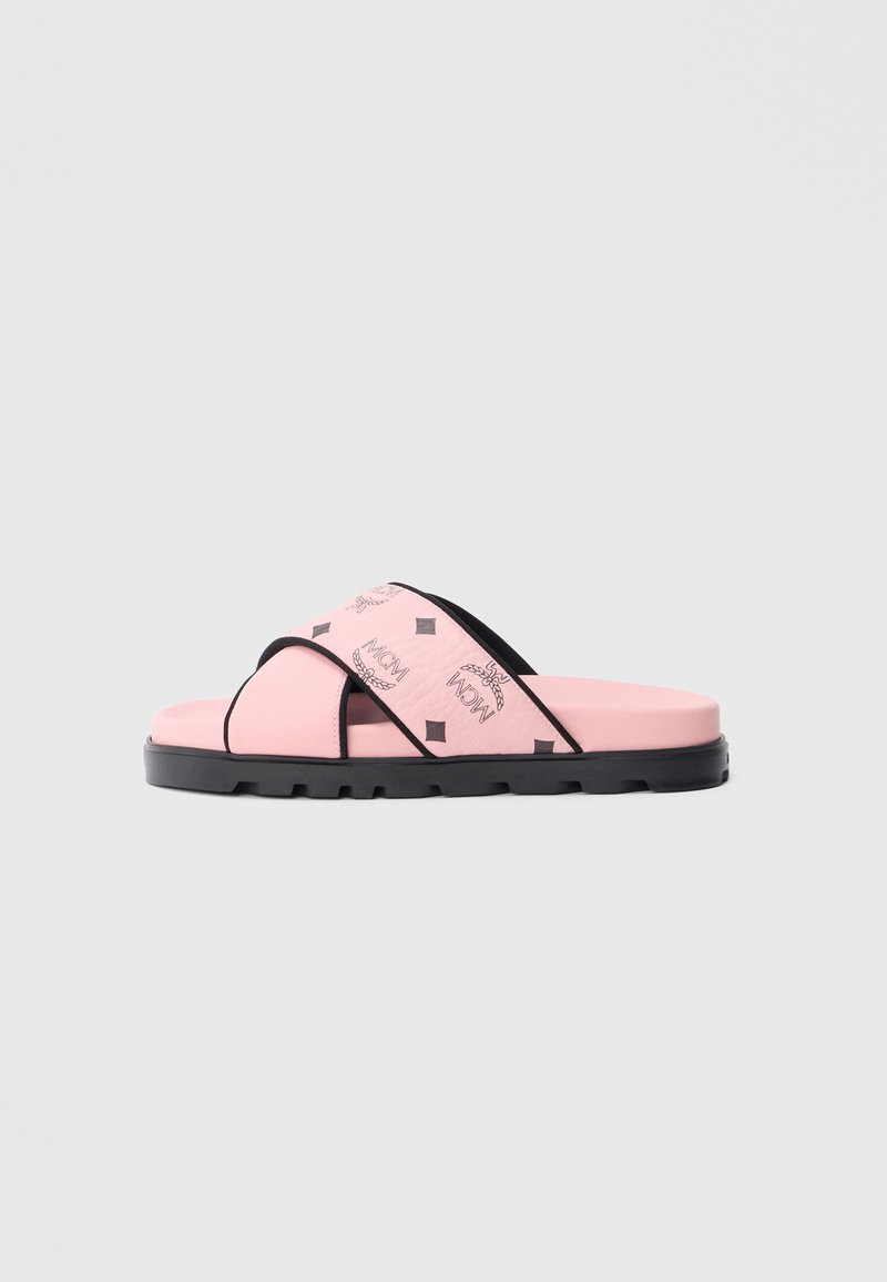 Lyserød slip-på sandaler med tekstureret overdelsmateriale, et sort logomønster, kontrasterende sorte stropper og en tyk sort sål med skridsikre egenskaber.