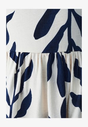 Květinová látka v navy a krémové barvě, s nařaseným lemem. Měkká textura s velkými listovými motivy po celé ploše.