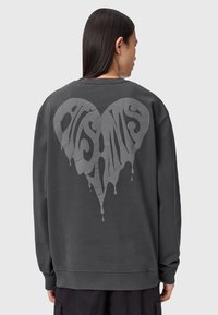 Grå sweatshirt med et stort, dryppende hjertegrafik på ryggen. Har lange ærmer og en afslappet pasform. Materialet er en bomuldsblanding.