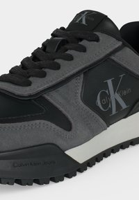 Χαμηλά μαύρα και γκρι αθλητικά Calvin Klein με υφασμένα κορδόνια, λογότυπο στην πλευρική επιφάνεια και ανθεκτική σόλα.