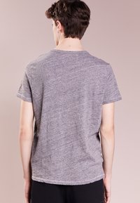 Grå t-shirt med kort ärm och rundad halsringning, mjuk textur och ledig passform, med en enkel baksida och sydd fåll längs botten.