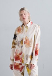 Camicia con stampa floreale bianca, caratterizzata da grandi fiori astratti multicolori. Maniche lunghe e colletto classico. Texture liscia.