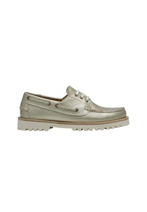 Chaussure bateau en cuir beige clair avec lacets à l’avant, couture moc toe, et semelle épaisse à crampons pour usage extérieur.