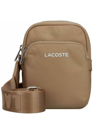 Bruine schoudertas met een gladde, stoffen buitenkant, een voorste ritsvak en een brede, gestructureerde band met de merknaam "LACOSTE."