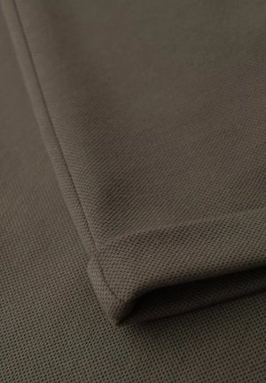 Tissu marron texturé avec un motif subtil, plié soigneusement sur le bord. Surface lisse avec un tombé doux et des détails de couture renforcée.