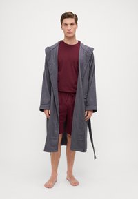 Grå bomullskåpe med hette, med brede ermer og knytbelte, over burgunder shorts og en matchende T-skjorte med rund hals.