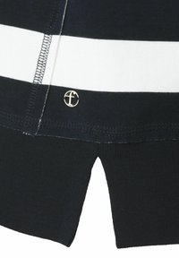 Chemise rayée en bleu marine avec des bandes blanches. Présente un bas noir côtelé et un accent logo doré. Tissu en coton doux avec des coutures visibles.