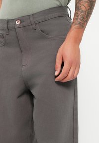 Gray cotton trousers with a straight-cut design. Features front and back pockets, a button closure, and visible stitching details.