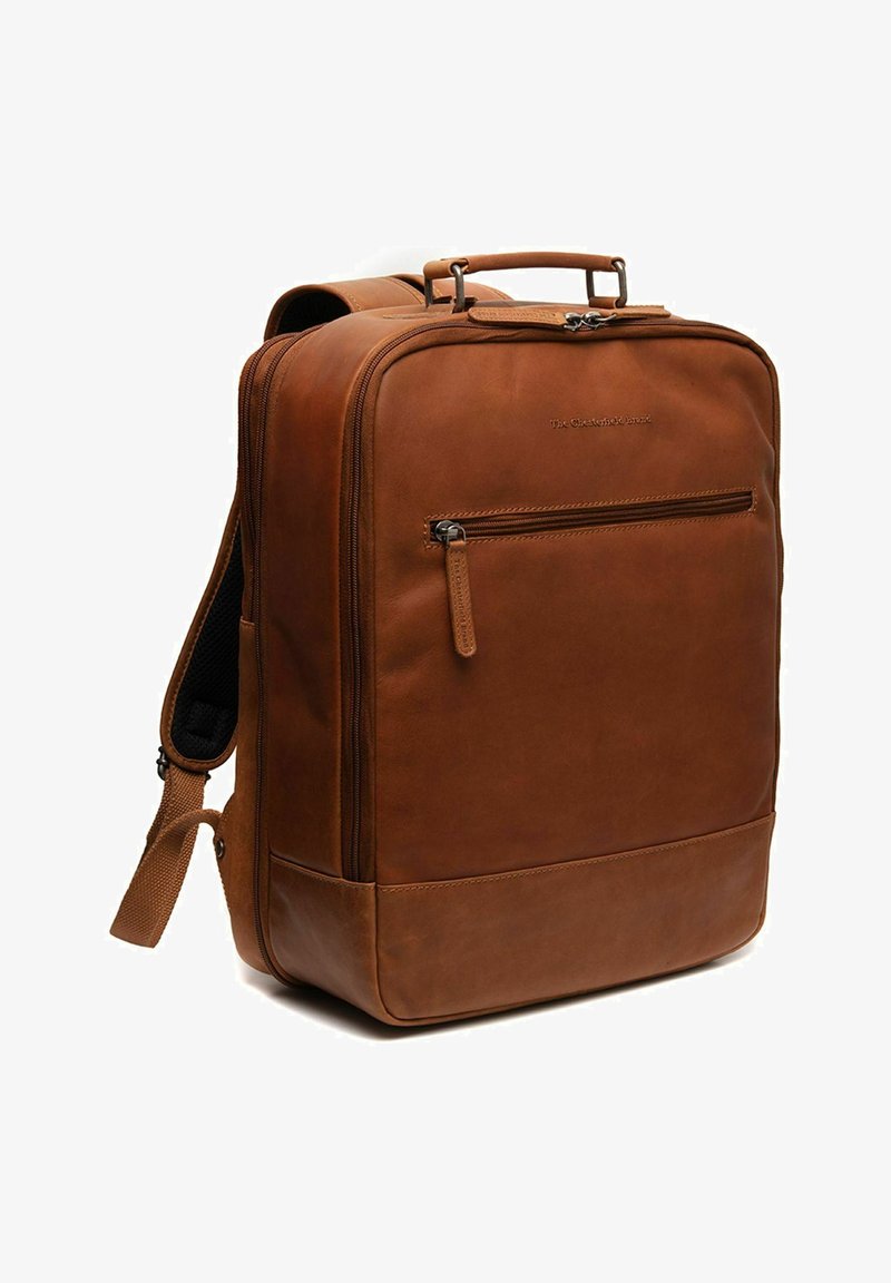 Mochila de cuero marrón con un diseño estructurado, bolsillo frontal con cremallera y correas ajustables y acolchadas. Textura suave y detalles minimalistas.