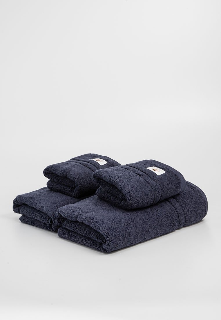 Marineblaue Baumwollhandtuchset, bestehend aus zwei Badetüchern und zwei Handtüchern. Strukturiertes Finish mit einem gefalteten Design und kleinen Etikettendetails.