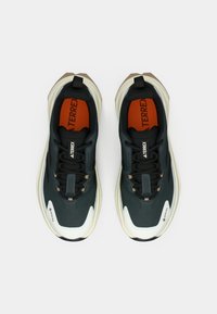 Σκούρα μπλε αθλητικά παπούτσια με κομψό σχεδιασμό, που διαθέτουν υφασμένο επάνω μέρος, πορτοκαλί λεπτομέρειες και λευκή λαστιχένια σόλα με χαρακτηριστικό σχήμα.