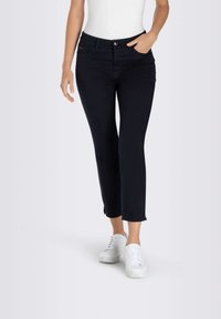 Jean skinny bleu marine avec une taille mi-haute, doté d'une fermeture à bouton avant, de cinq poches et de détails à l'ourlet brut au niveau des chevilles.