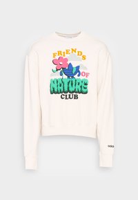 Felpa color crema con design corto. Presenta un testo grafico colorato "AMICI DELLA NATURA" e illustrazioni floreali. Accenti blu e rosa.