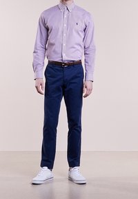 Knapp-up skjorta med lila och vita ränder, marinblå chinos och vita sneakers, med en klassisk krage och ett bälte. Slim fit-design.