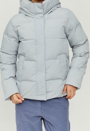 Osoba ubrana w jasnoszarą puchową kurtkę z przednimi kieszeniami i kapturem, w połączeniu z niebieskimi sztruksowymi spodniami na jednolitym tle.