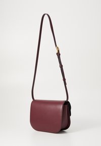 Borsa a tracolla in pelle bordeaux con pattina curva, tracolla regolabile e hardware in tono oro. Texture liscia con dettagli di design minimali.
