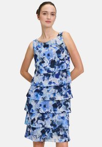 Kwiatowa sukienka z falbanami w odcieniach niebieskiego, z warstwami falbanek i okrągłym dekoltem. Wykonana z lekkiego materiału o gładkiej teksturze.