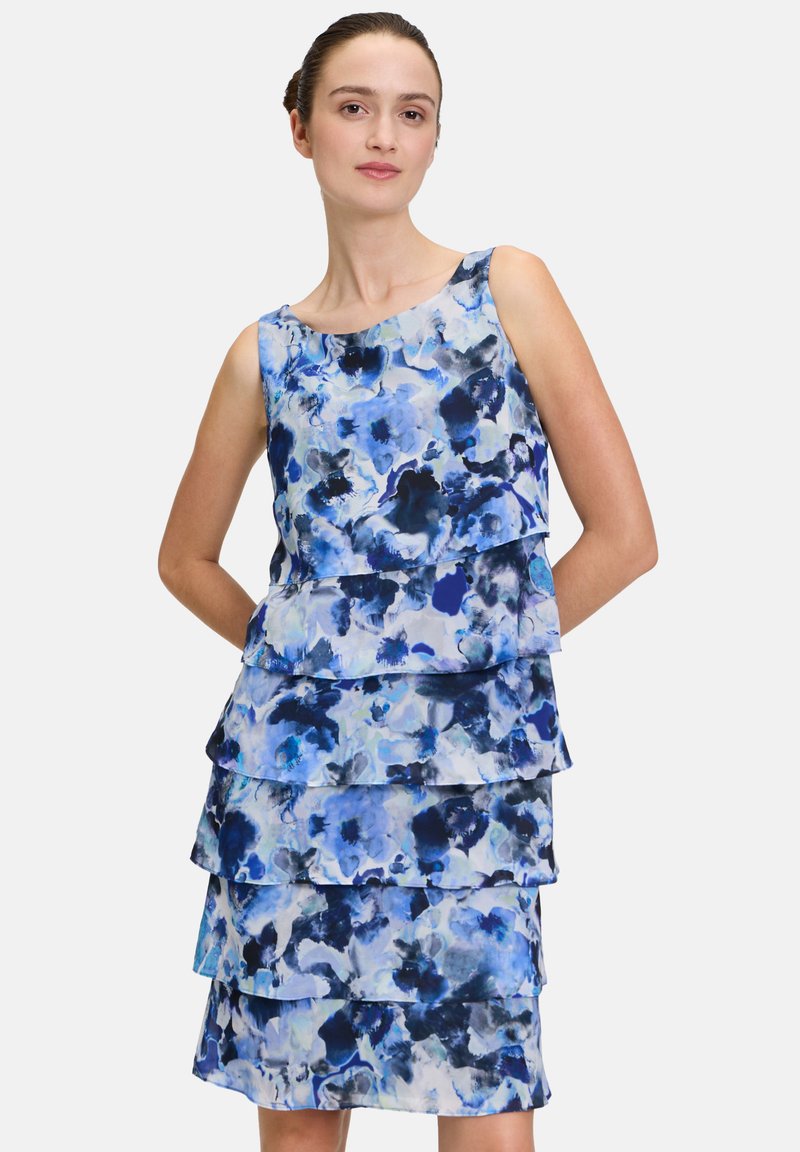Kwiatowa sukienka z falbanami w odcieniach niebieskiego, z warstwami falbanek i okrągłym dekoltem. Wykonana z lekkiego materiału o gładkiej teksturze.