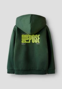Felpa verde scuro con grande testo giallo-verde "PURPOSE" sulla schiena, caratterizzata da frasi motivazionali più piccole attorno alla parola.