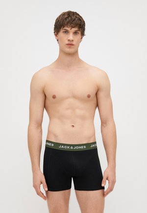 Czarne bokserki z zielonym pasem oznaczonym "JACK & JONES". Materiał wydaje się gładki, z dopasowanym krojem. Model jest bez koszulki.