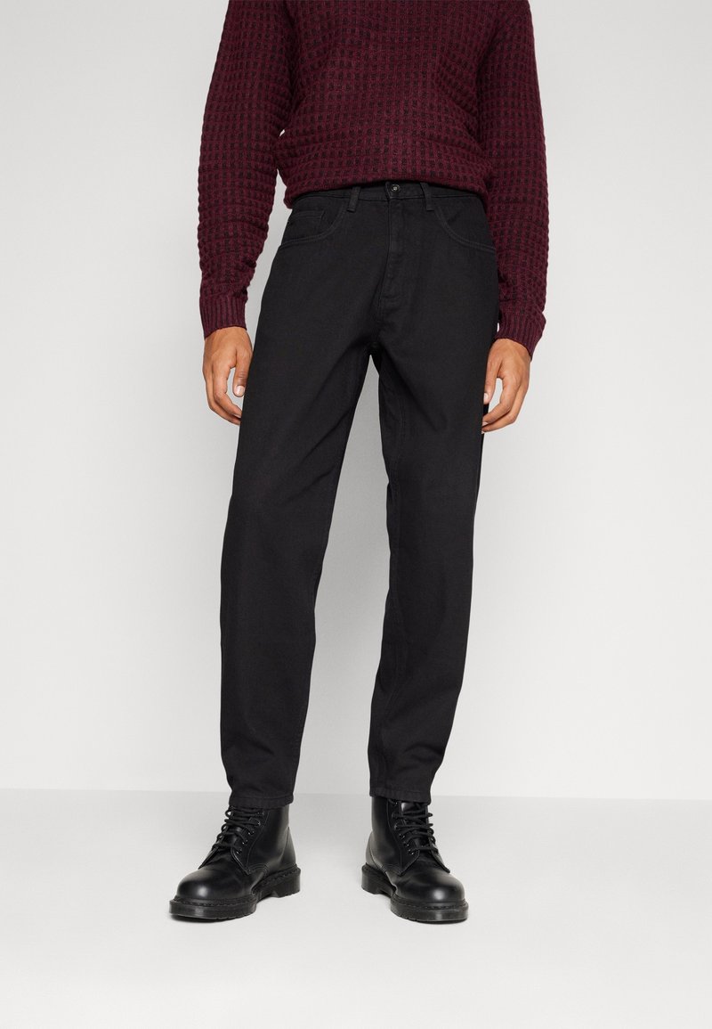 Musta suora lahkeinen farkut puuvilladenimistä, joissa on klassinen viiden taskun muotoilu ja nappikiinnitys. Yhdistetty burgundinväriseen teksturoidusta neulepaidasta.