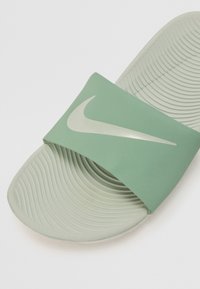 Grön halksandaler med ett tjockt, slätt rem som har en kontrasterande vit logotyp. Texturerad fotbädd för grepp och komfort.