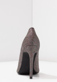 Des chaussures à talons hauts avec un extérieur en paillettes multicolores, un bout pointu et une semelle noire. Le talon aiguille ajoute de la hauteur et de l'élégance.